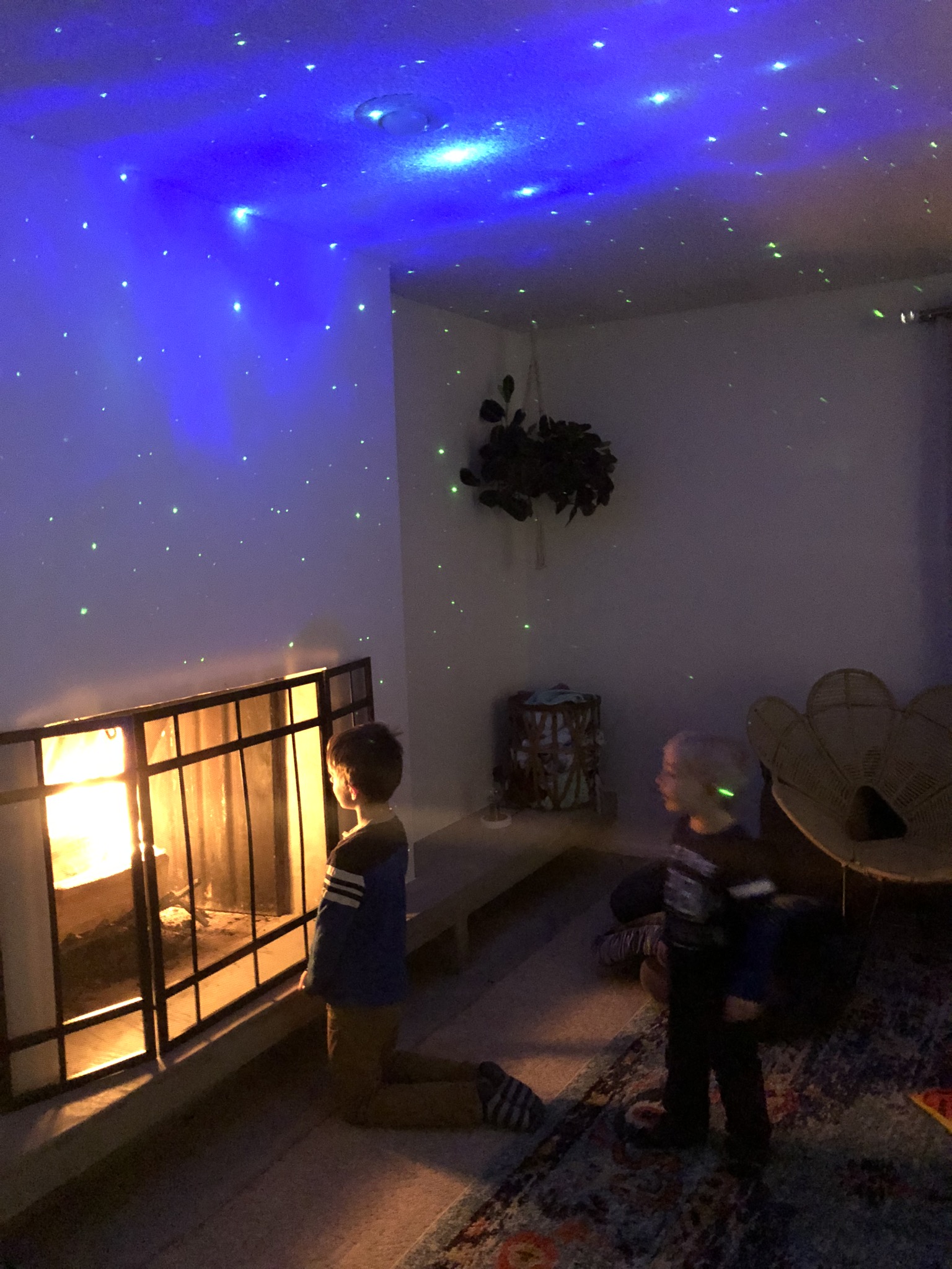 Kids in living room looking at fire in fireplace stars projected on ceiling 