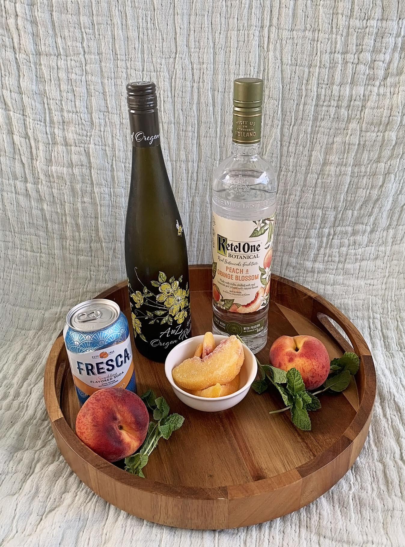 Ingredients of Peach and Orange Blossom Sangria including frozen sliced peaches, mint, peach and citrus soda, reisling, and peach and orange blossom voda.