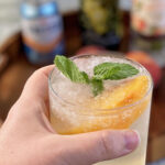 This peach and orange blossom sangria is served over crushed ice and topped with mint and a sliced peach.