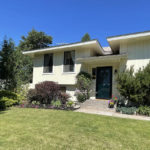 yellow split level home with green grass and landscaping