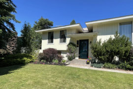 yellow split level home with green grass and landscaping