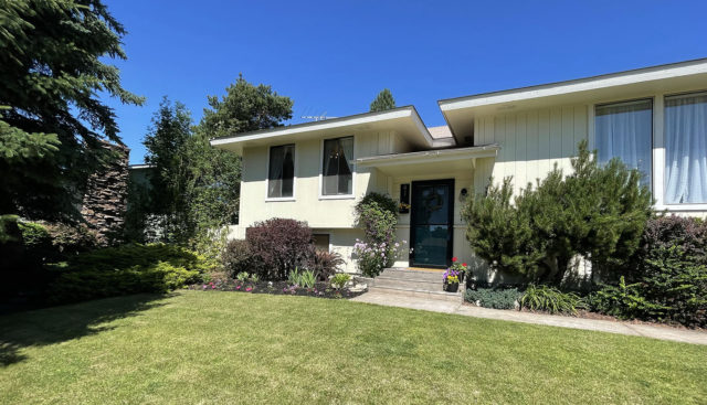 yellow split level home with green grass and landscaping