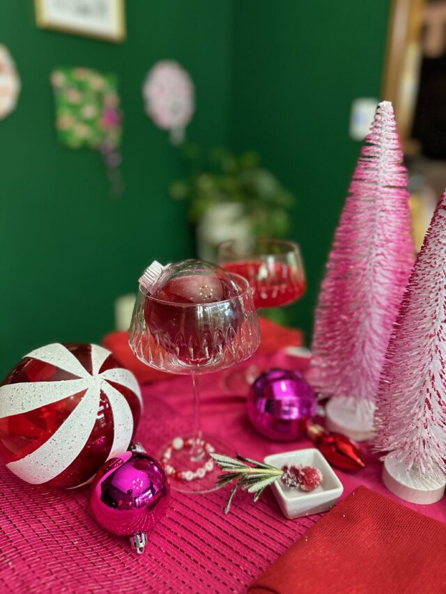 Holiday cocktail in christmas bauble with pink and red decor